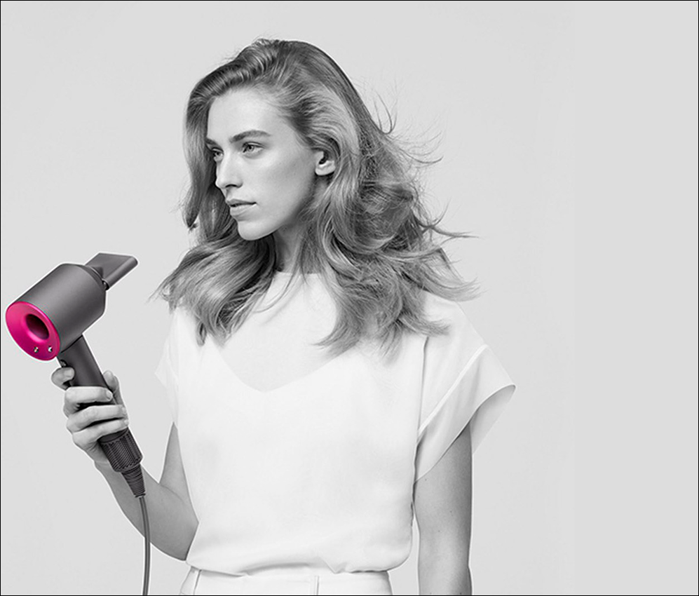 Девушка сушит волосы феном dyson